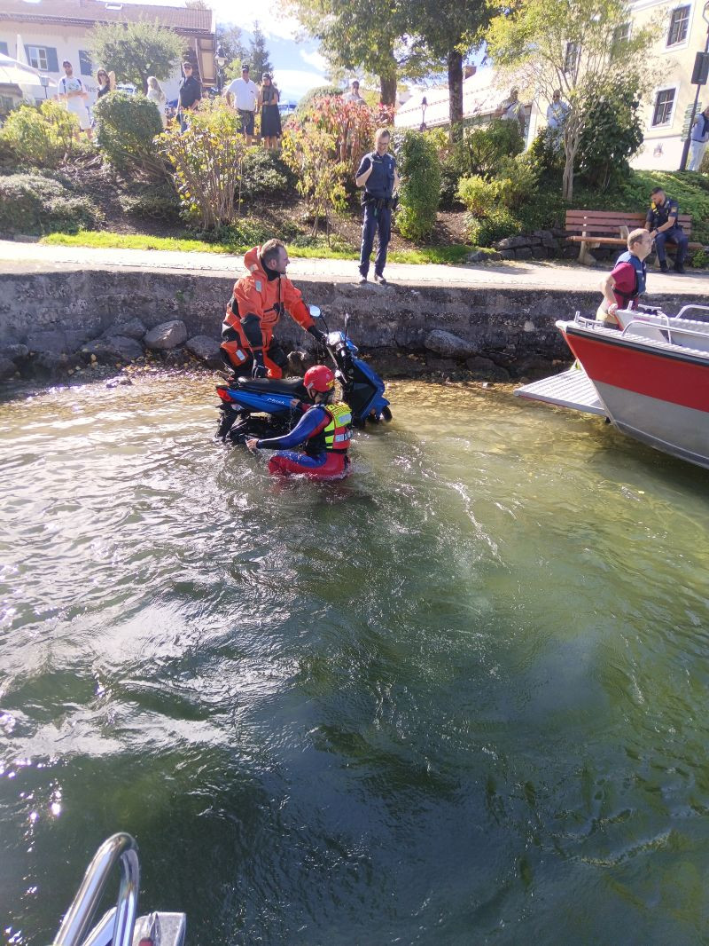 eine DLRG-Wasserretterin mit einem Feuerwehrmann beim Aufrichten des Rollers