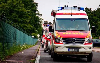 Mehrere Einsatzfahrzeuge fahren hintereinander auf die Kamera zu (rechte Bildhälfte)