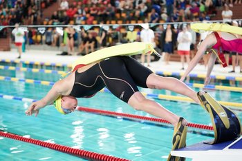 Rettungssportler beim Startsprung mit Flossen und Rettungsgerät.