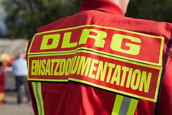 Rücken Einsatzperson rote Jacke mit gelber Aufschrift "DLRG Einsatzdokumentation"