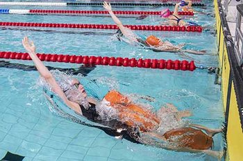 Rettungssportlerin stößt sich im Wasser mit Puppe vom Rand ab